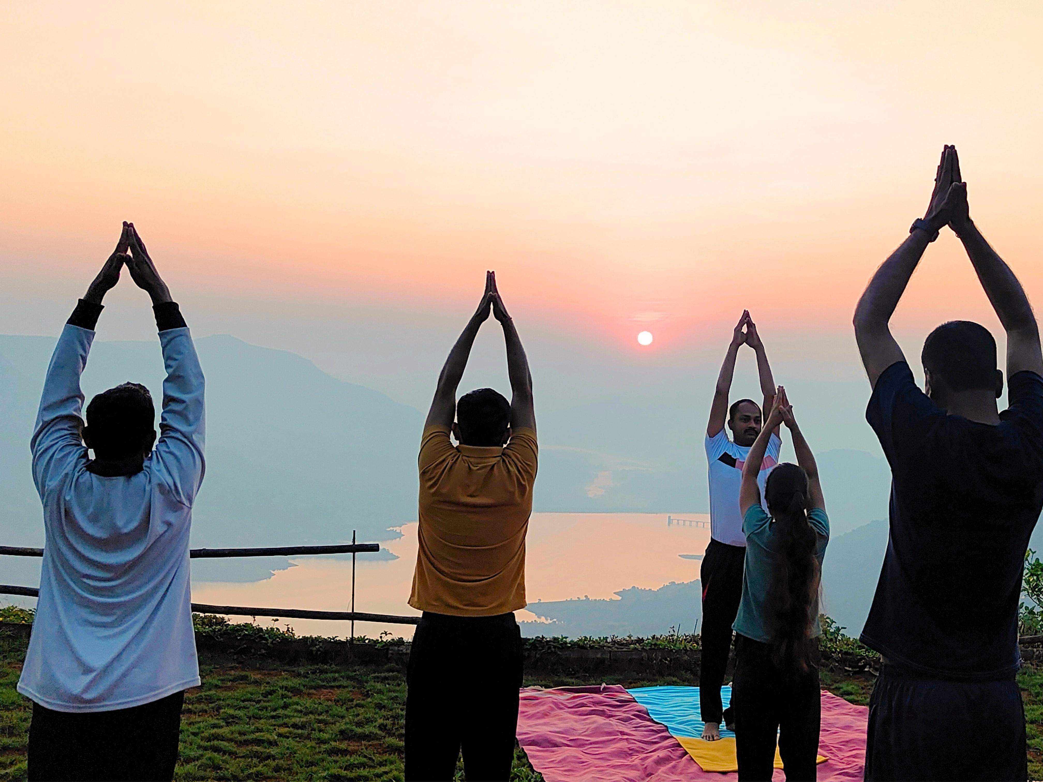 Guests participating in a guided yoga session at sunrise with scenic valley views.